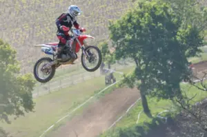 Motocross rider in protective equipment jumping over a track
