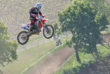 Motocross rider in protective equipment jumping over a track