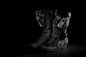 Pair of black motorcycle riding boots on a dark background